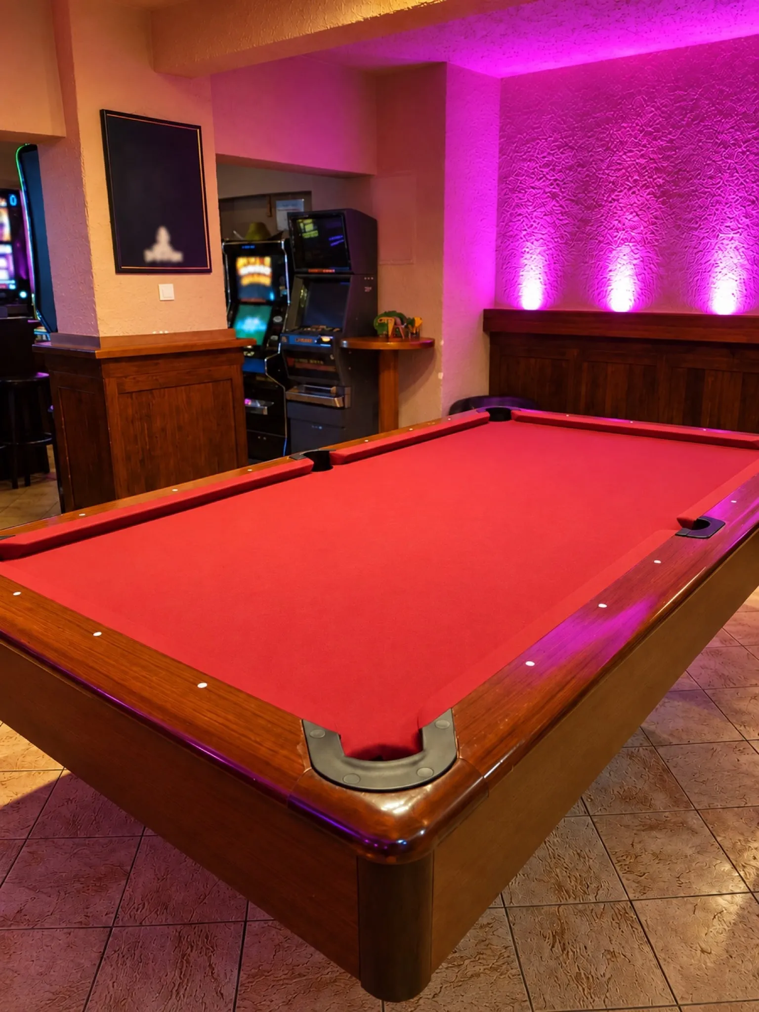 Pool table with red cloth in front of a pink wall