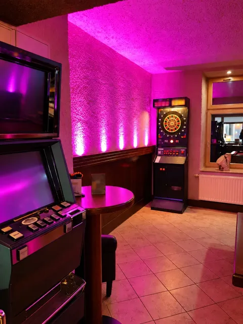 Dart machine in pink lighting next to a gaming machine