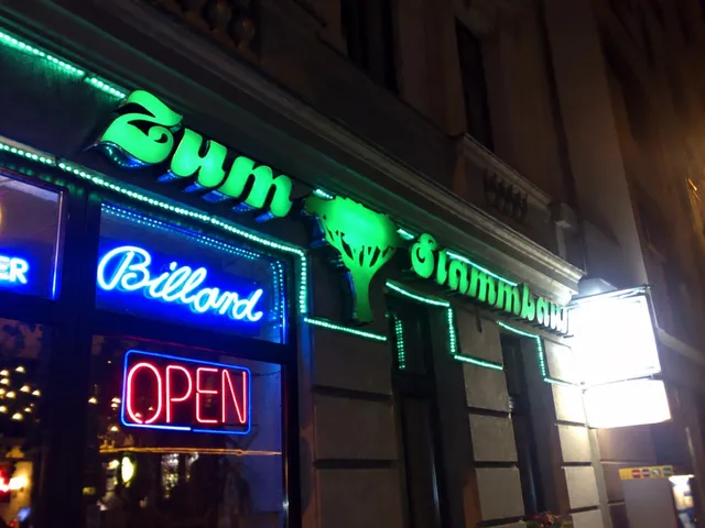 Illuminated “Zum Stammbaum” sign and pool neon at night