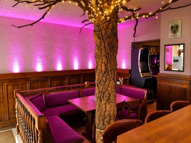 Seating corner with purple upholstered benches under the tree, pink wall lighting