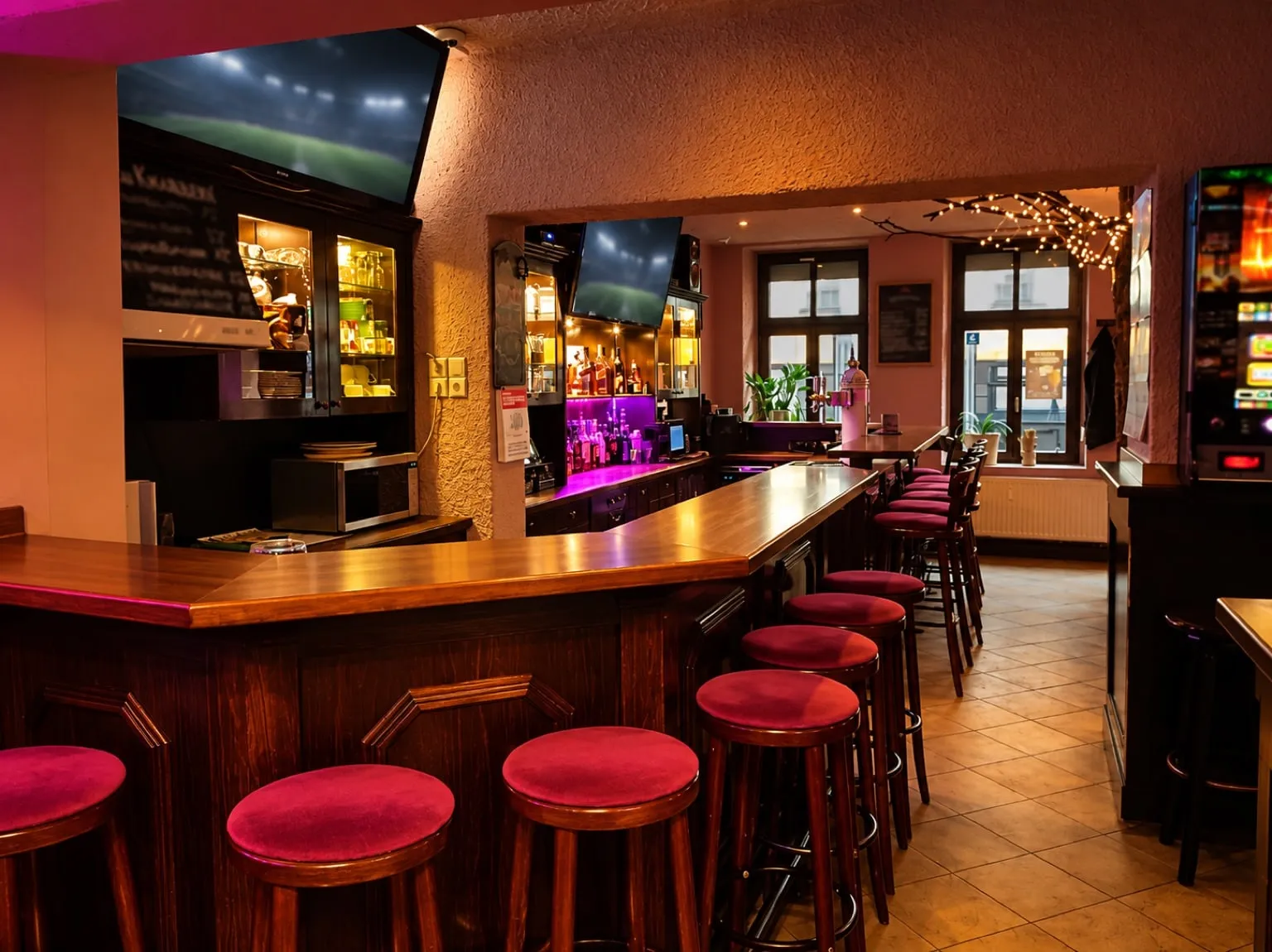 Long wooden bar with red stools and a wall of bottles