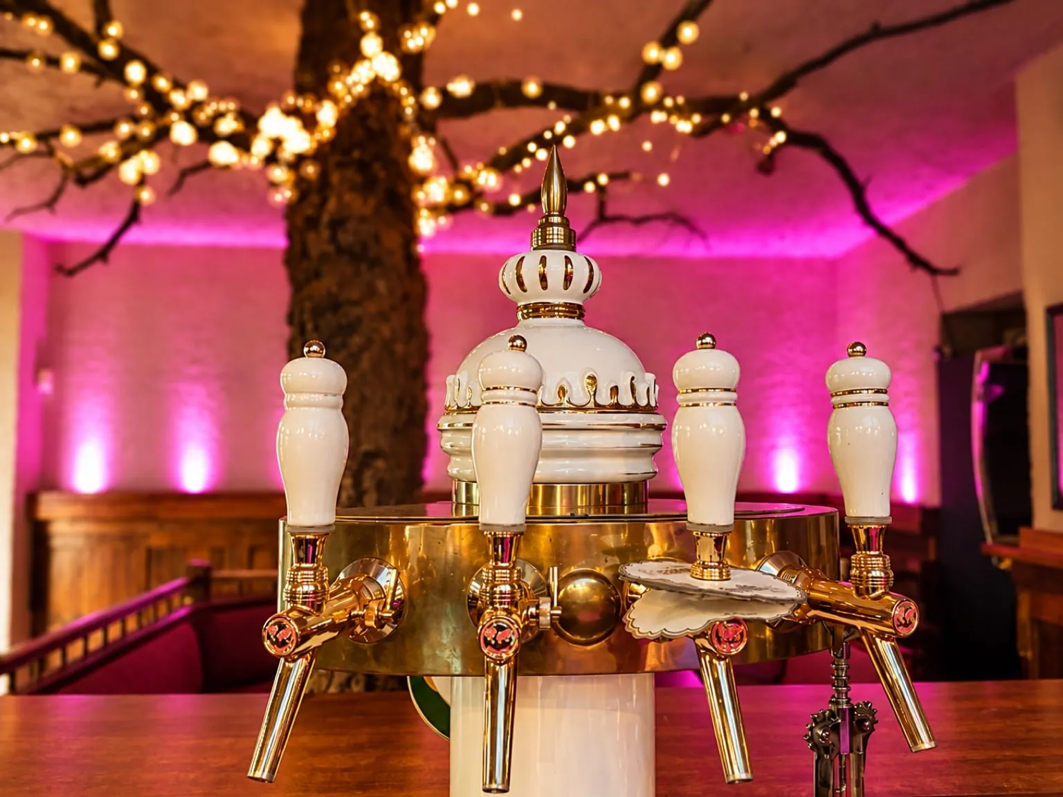 Beer taps with a white ceramic tower in front of the lit tree